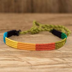 a multicolored bracelet is sitting on a wooden table and it's made out of string