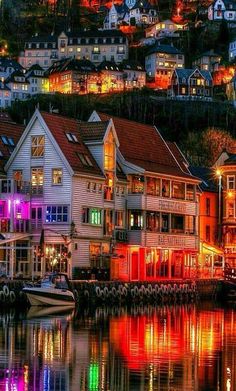 colorful buildings are lit up at night by the water