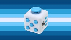 a white dice with blue dots on it sitting in front of a blue and white striped background