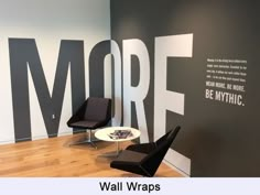 two black chairs sitting on top of a hard wood floor next to a wall with words painted on it