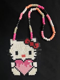 a hello kitty beaded purse with a pink heart on the front and black background