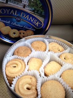 a tin filled with lots of cookies next to a can of royal danish butter glaze