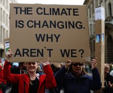 people holding up signs in the middle of a street with words on them that read, the climate is changing why aren't we?