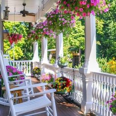 the porch is covered with flowers and rocking chairs