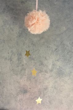 a pink pom - pom hanging from a string with gold stars on it