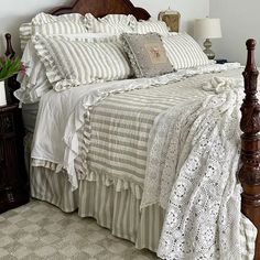 a bed with white and grey striped comforter on top of it next to a night stand