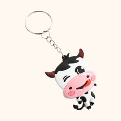 a cow shaped keychain hanging from a metal hook