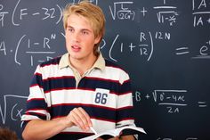 a young man standing in front of a blackboard