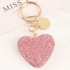 a pink heart shaped keychain sitting on top of a white table