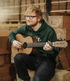 a man with glasses is playing an acoustic guitar