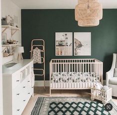 a baby's room with green walls, white furniture and pictures on the wall