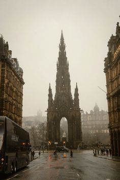 a city street filled with traffic next to tall buildings in the foggy day time