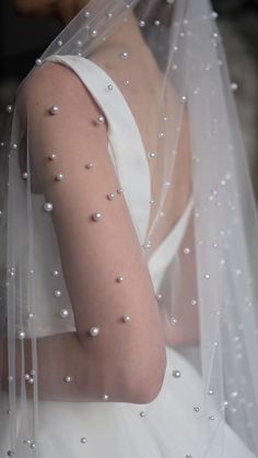 a woman wearing a veil with pearls on it