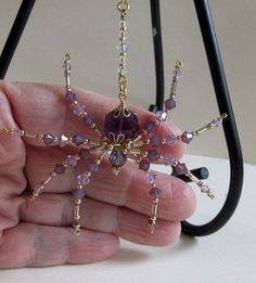 a hand holding a purple beaded spider ornament