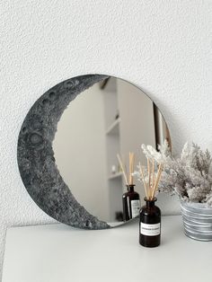 a mirror sitting on top of a table next to a vase with flowers in it