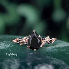 a black diamond ring sitting on top of a green leafy surface with leaves in the background