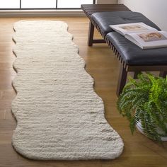 a large white rug on top of a hard wood floor next to a chair and window