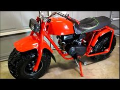 an orange motorcycle parked in a garage next to a wall with a black seat on it