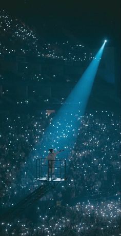 a man standing on top of a stage holding a microphone in front of a crowd