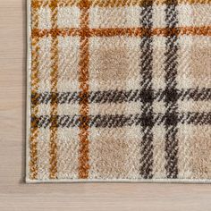 a brown and white plaid rug on top of a wooden floor