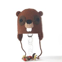 a crocheted brown bear hat with ears and nose is hanging on a hook