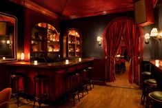 a dimly lit bar with red curtains and stools