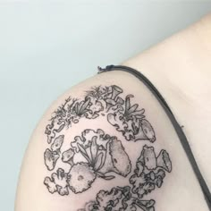 a close up of a tattoo on the back of a woman's shoulder with flowers and leaves