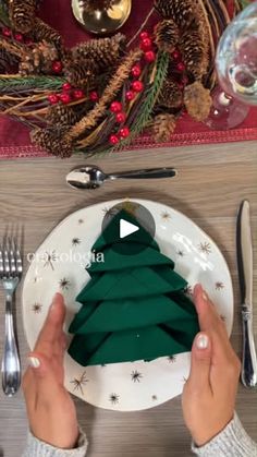 a person holding a plate with a green christmas tree on it and silverware in front of them