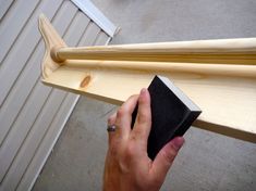 a person is holding a piece of wood with a sanding block next to it