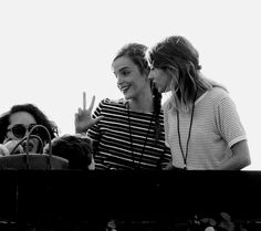 three women standing next to each other on top of a tennis court with their hands in the air