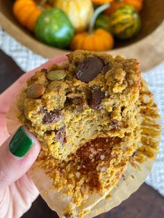 a person holding up a cookie in front of some pumpkins and gourds