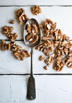 a spoon full of walnuts sitting on top of a white table