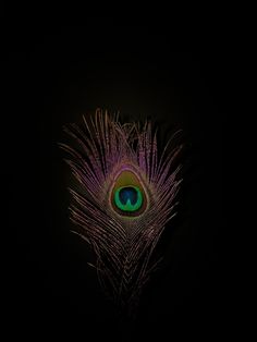 a peacock's eye is lit up in the dark with its feathers spread out