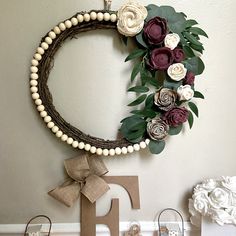 a wreath with flowers on the wall next to two small bags and some paper letters