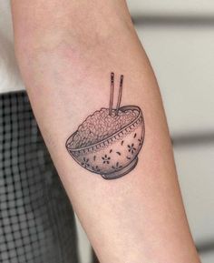 a tattoo with a bowl of rice and chopsticks on the arm by person