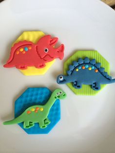 three cookies shaped like dinosaurs sitting on top of a white table next to each other