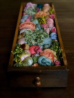 a wooden box filled with yarn and flowers