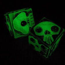 two dices that are glow green in the dark, one with a skull on it