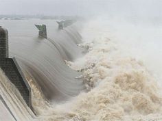 a large amount of water gushing over the side of a dam