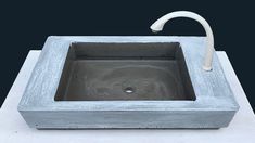 a square concrete sink with a white faucet