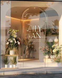 the front window of a flower shop with flowers in vases