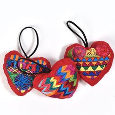 two red heart shaped ornaments hanging from black cords on a white background, one with an ornament in the shape of a heart