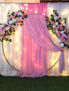 a decorated stage with pink drapes and white flowers on it's back wall