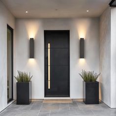 two black planters sitting on the side of a white wall next to a door