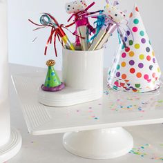 party hats and confetti sticks in a cup on a table