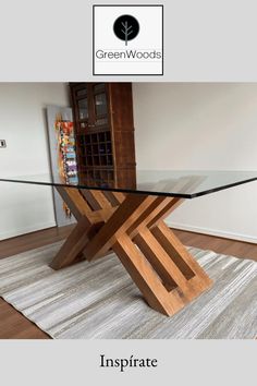 a glass table with wooden legs in the middle of a living room and an area rug on the floor