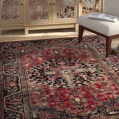 a large rug with an ornate design in red, blue and black colors on the floor