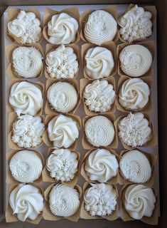 twelve cupcakes with white frosting in a box