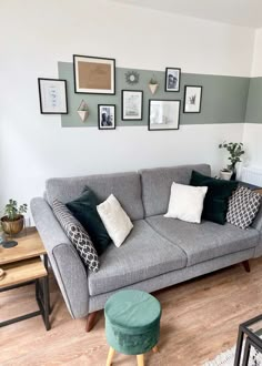 a living room with grey couches and pictures on the wall above them in various frames