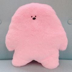 a pink teddy bear sitting on top of a blue couch